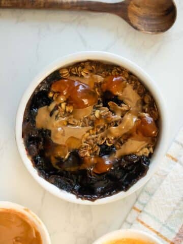 air fryer baked oats with peanut butter, blueberries, and jelly in a ramekin on a white table