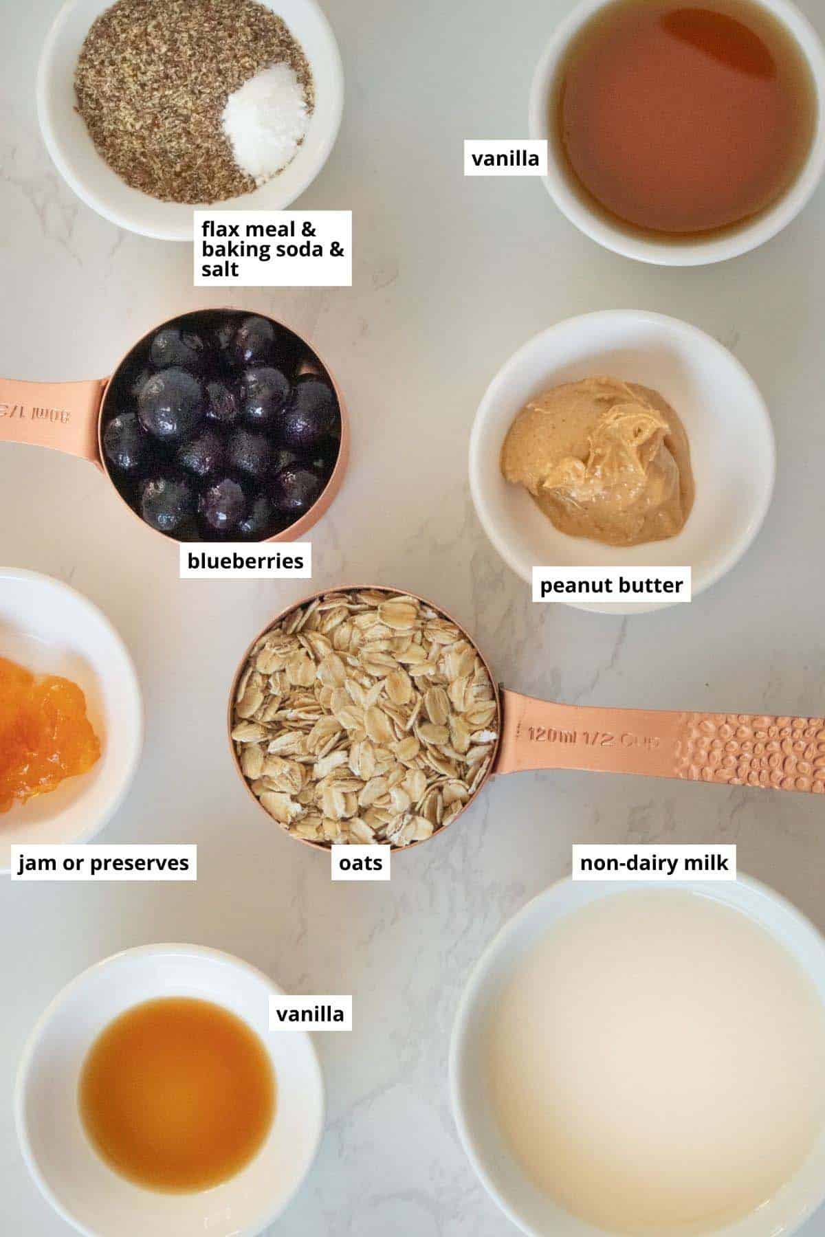 oats, peanut butter, jelly, blueberries, and other ingredients in cups on a white table