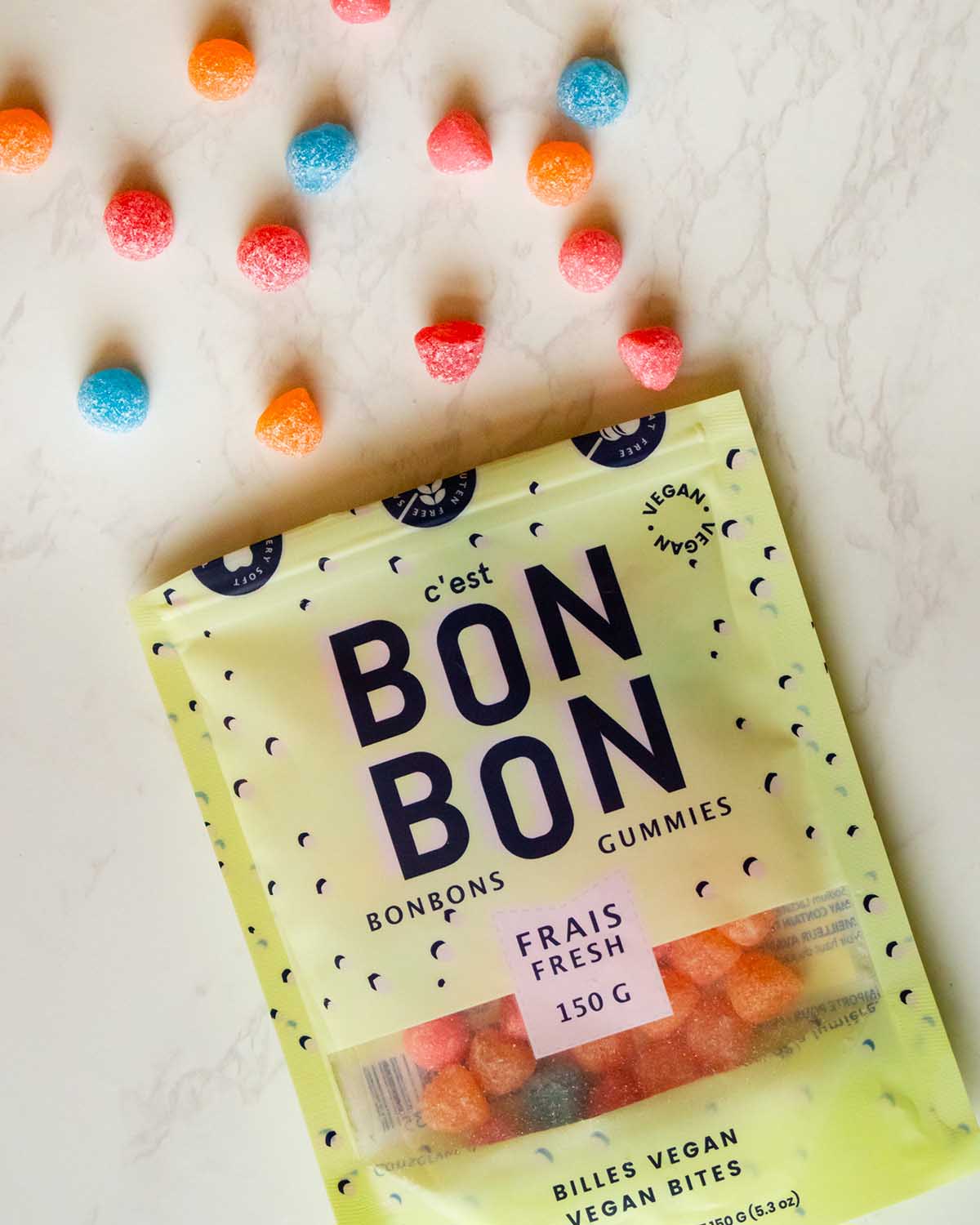 bag of C'est Bon Bon gummies with vegan gummies spilling out onto the white table