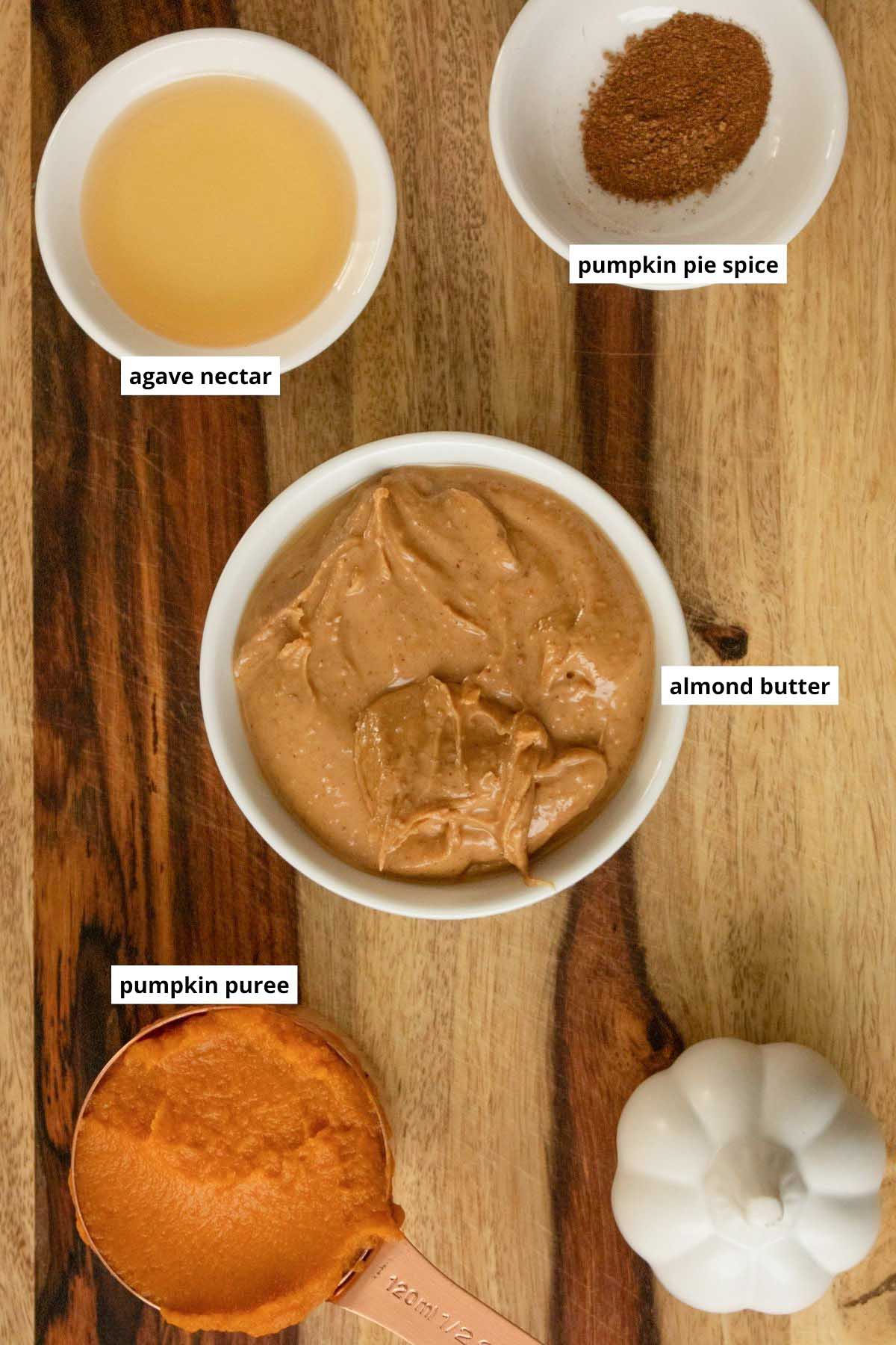 almond butter, pumpkin puree, pumpkin spice, and agave nectar in cups on a wooden table