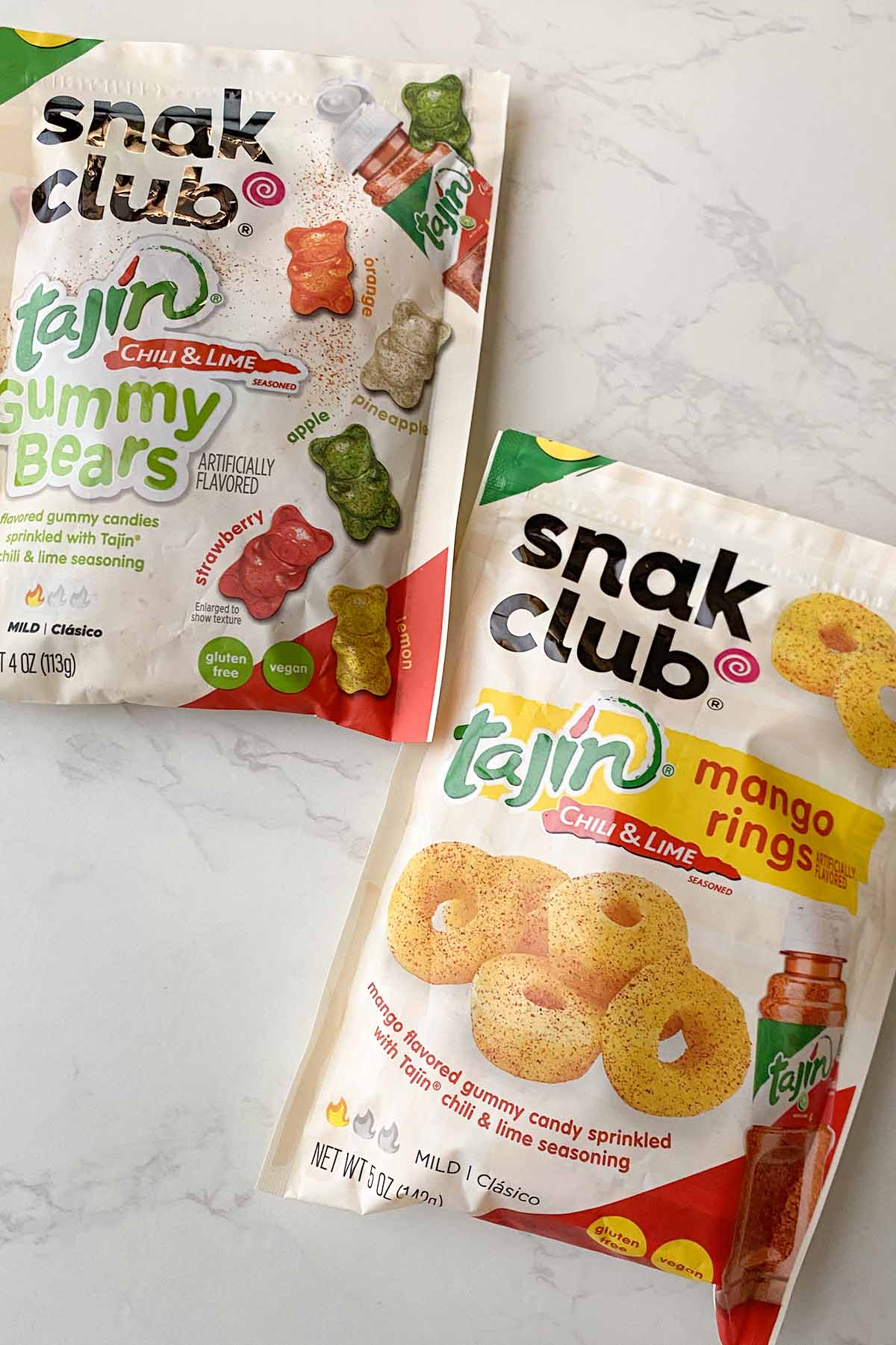 bags of Snak Club vegan gummy bears and mango rings on a white table