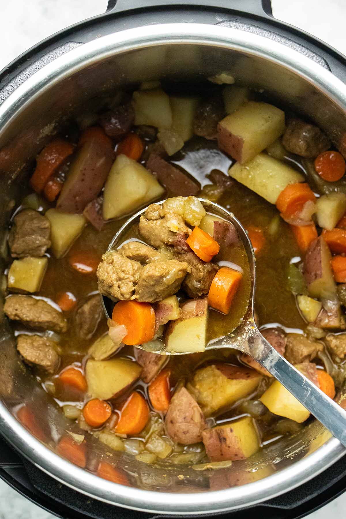 ladle serving vegan beef stew out of an Instant Pot