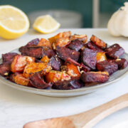 air fryer roasted beets on a plate with a spoon and with lemon and garlic in the background