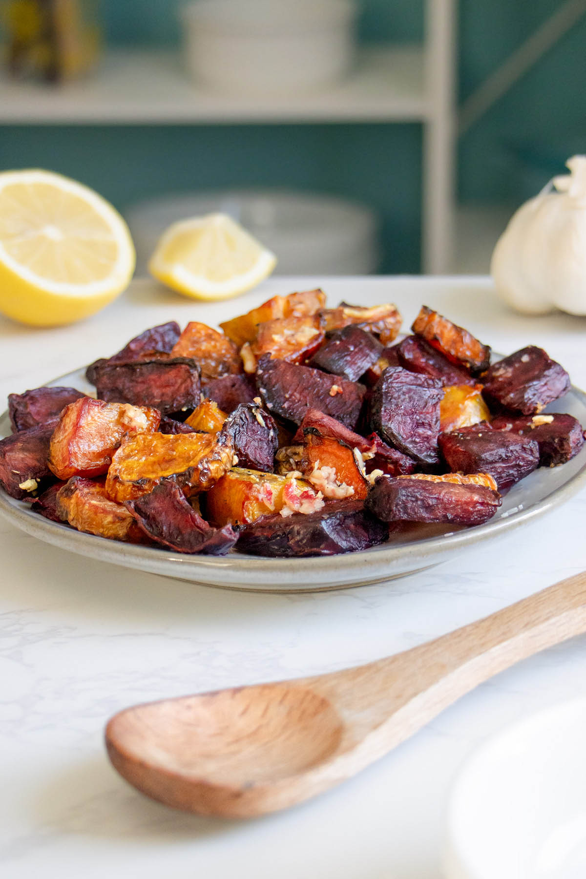 air fryer roasted beets on a plate with a spoon and with lemon and garlic in the background
