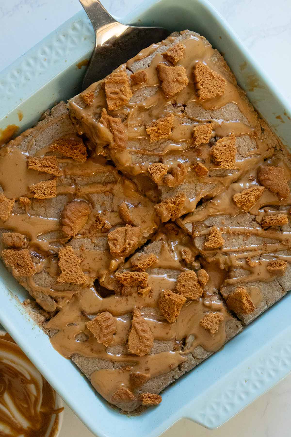 pan of Biscoff baked oats with a spatula serving a slice