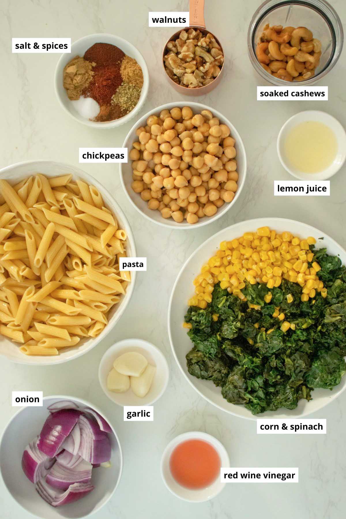 pasta, chickpeas, walnuts, and other chorizo pasta ingredients in bowls on a white table
