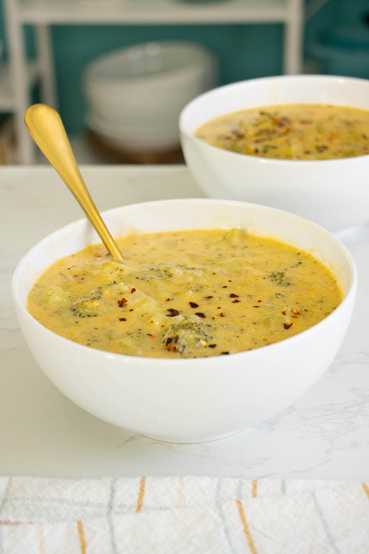 bowls of vegan Instant Pot broccoli cheddar soup with crushed red pepper on top