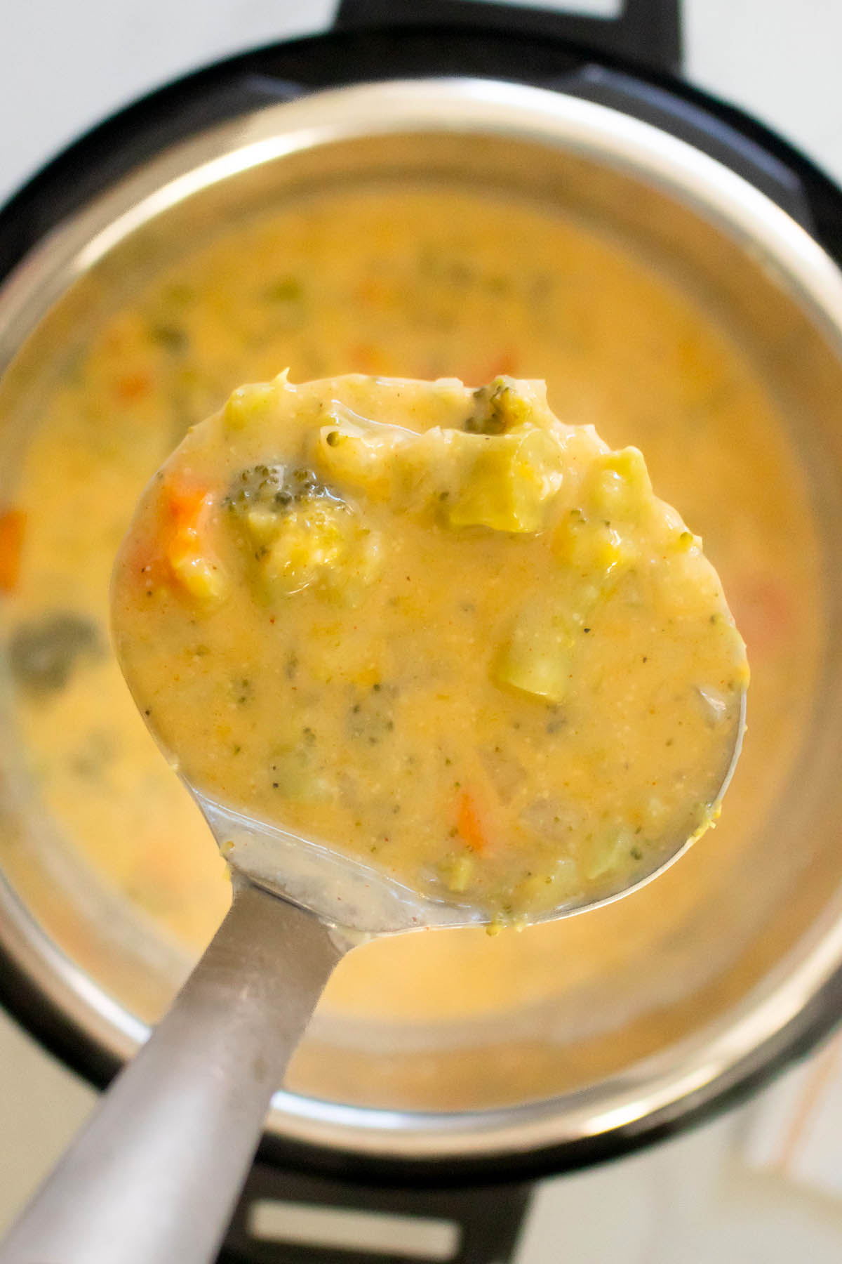 ladle serving vegan broccoli cheddar soup from an Instant Pot