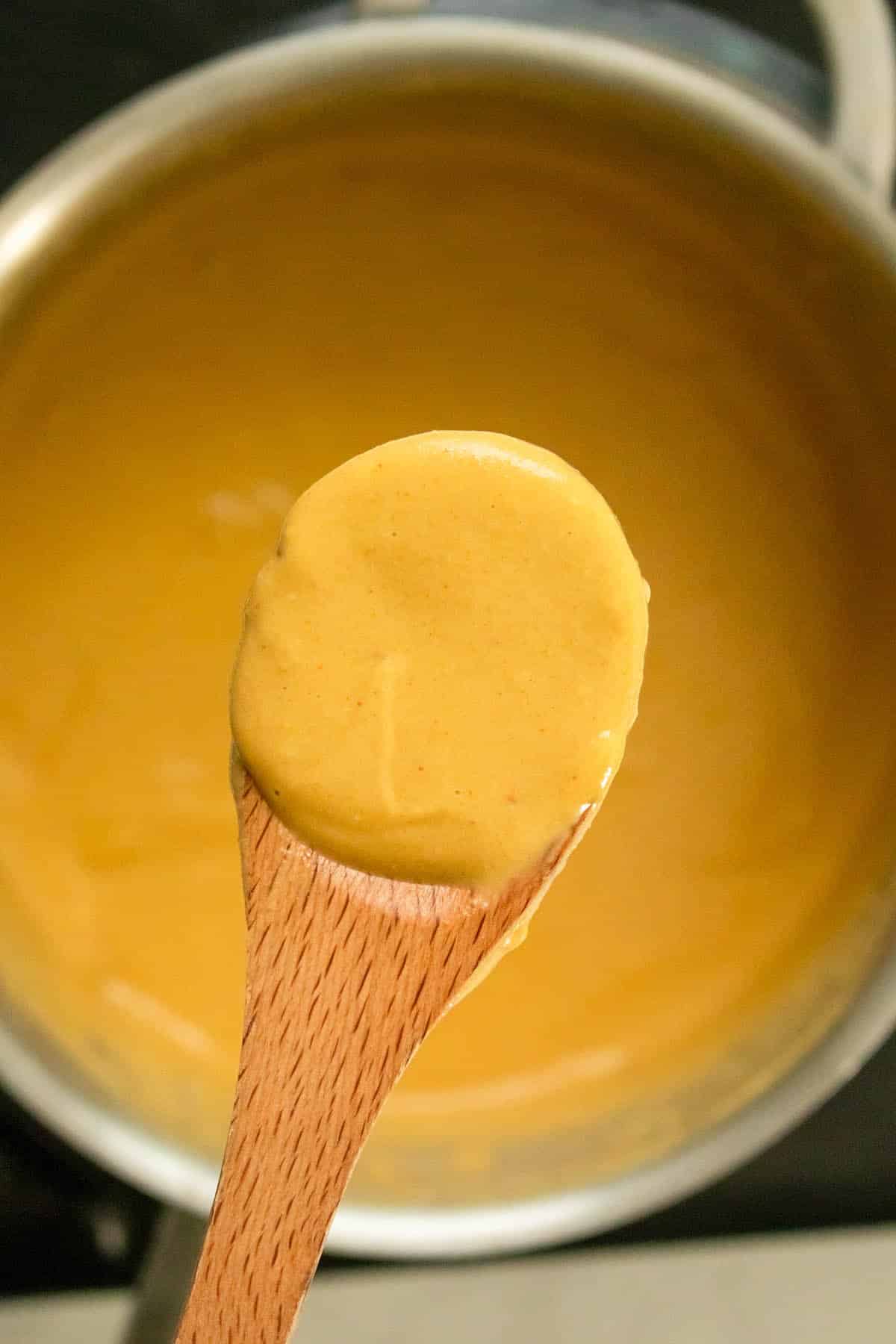 scooping up a spoonful of nooch cheese sauce from the pan