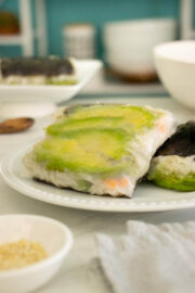 rice paper sushi with avocado and pickled carrots on a white plate
