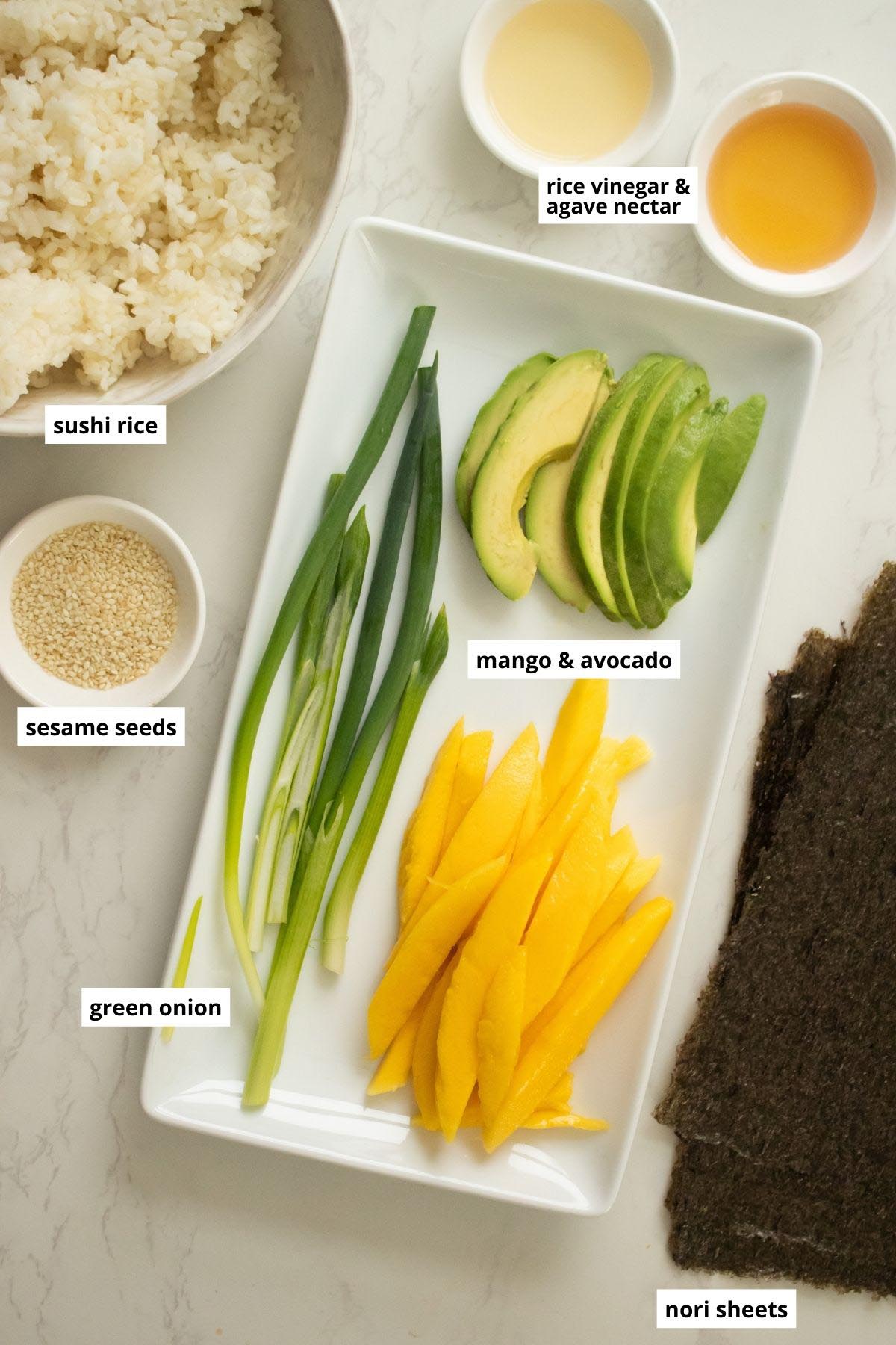 mango, avocado, green onion, and other sushi ingredients on a white table