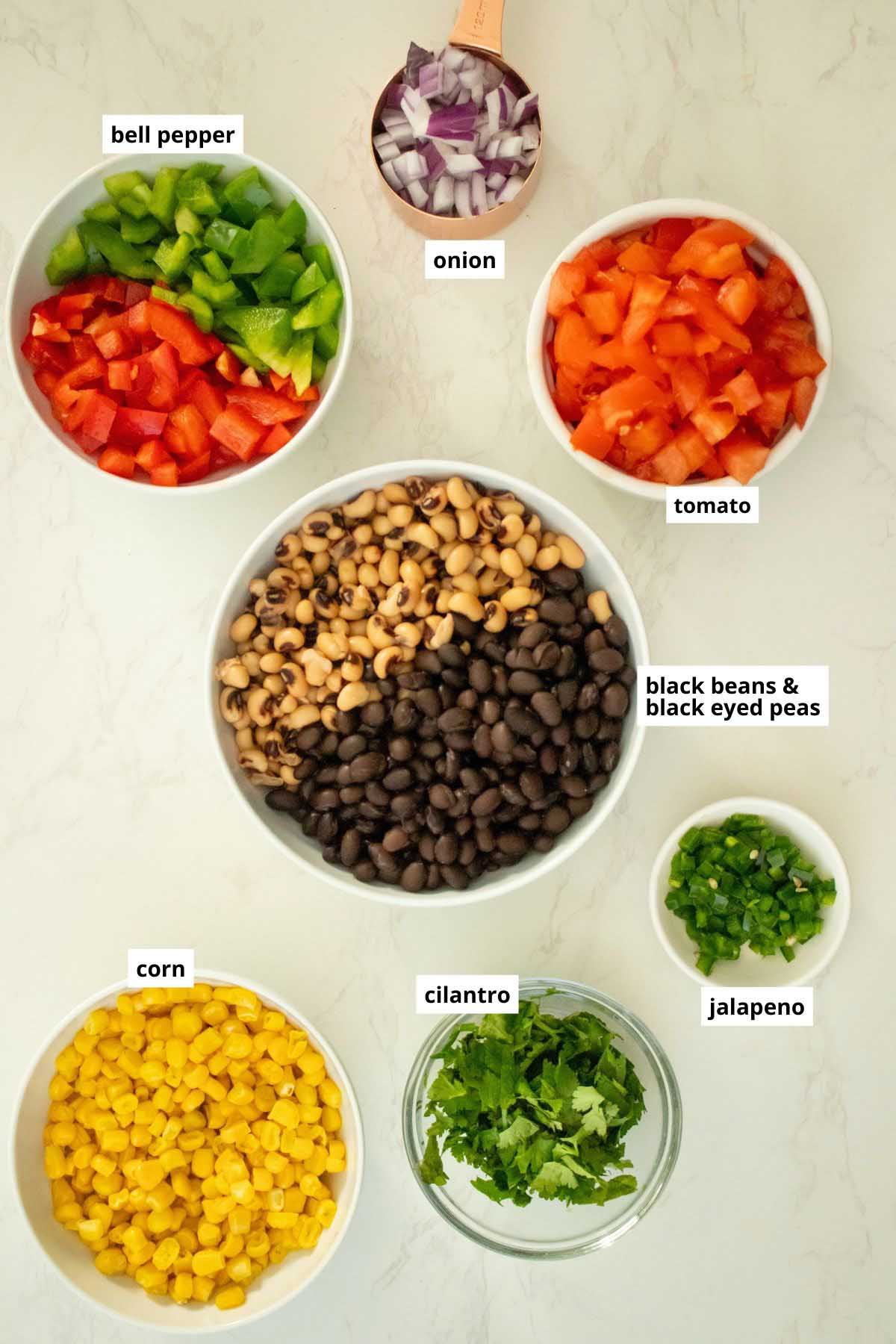 black eyed peas, black beans, and other cowboy caviar ingredients in bowls on a white table