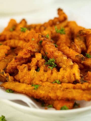 air fryer frozen sweet potato fries on a serving tray after cooking and seasoning