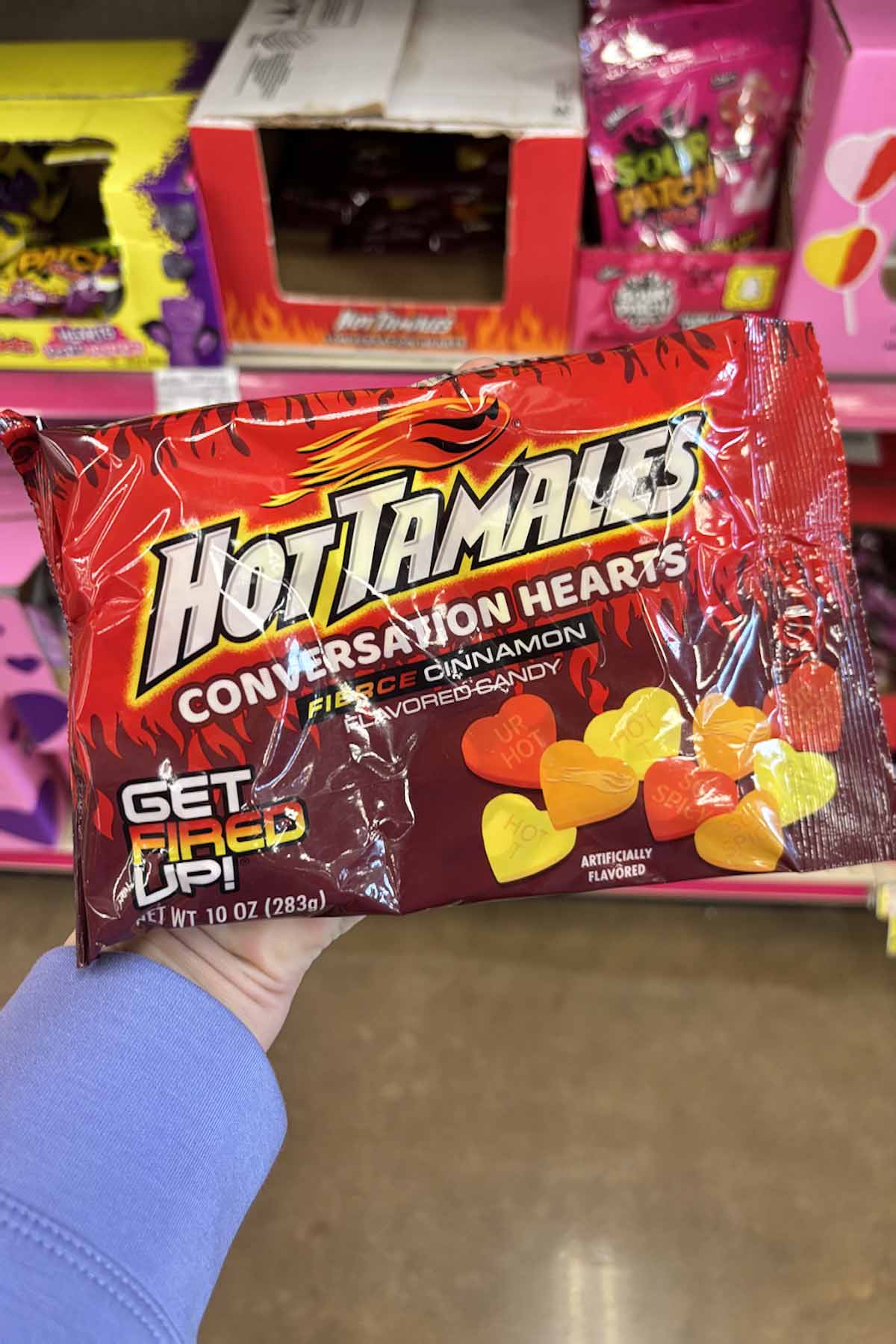 hand holding a bag of Hot Tamales conversation hearts