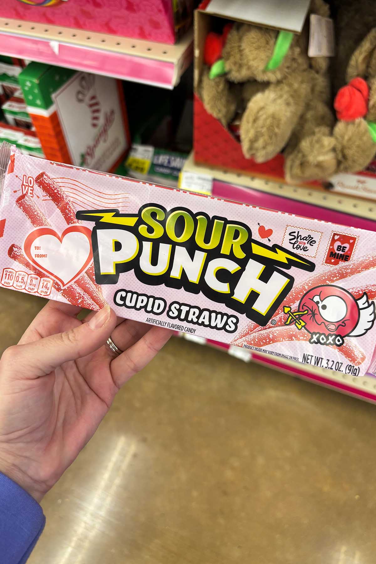hand holding a package of Sour Punch Cupid Straws