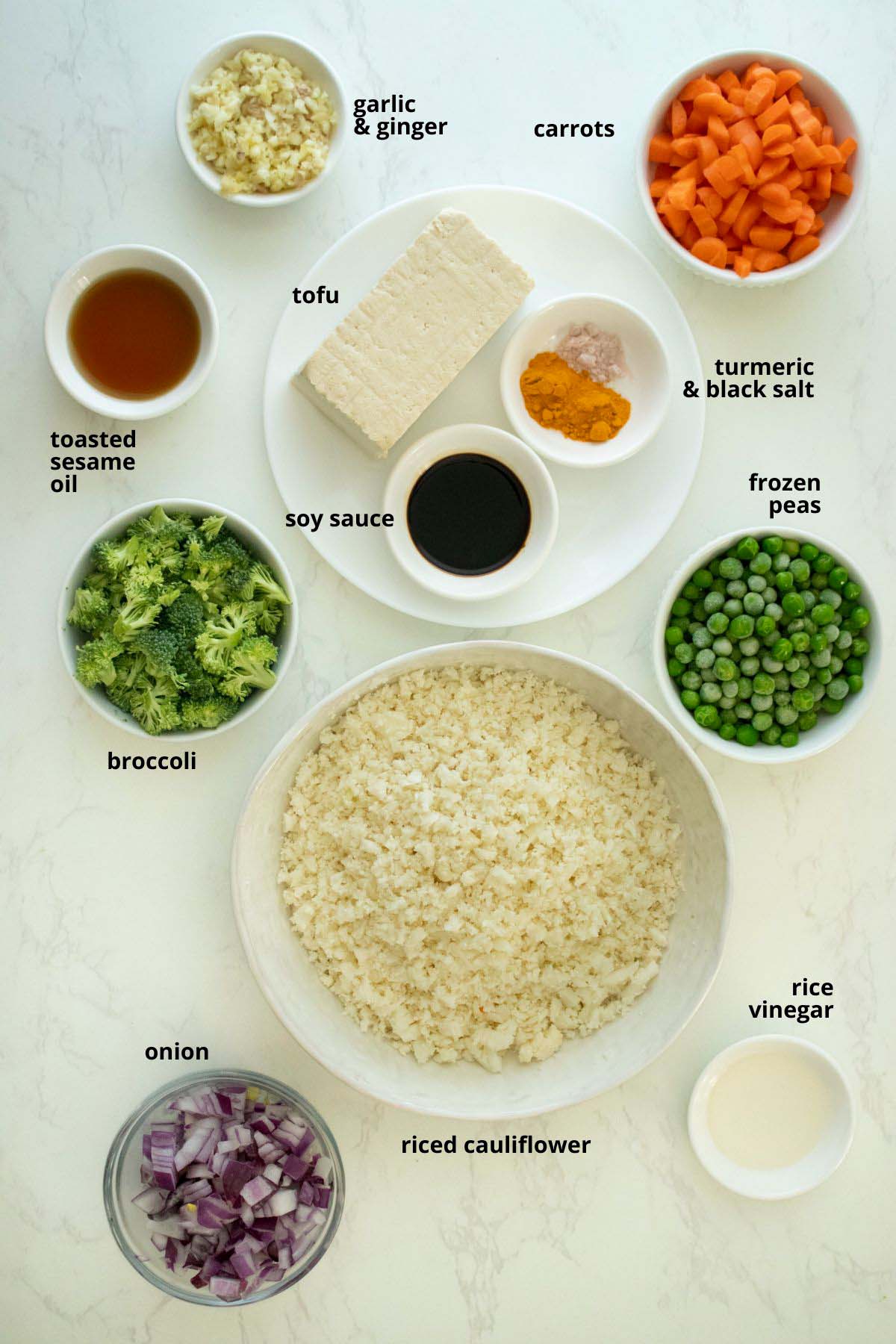 riced cauliflower, other veggies, tofu, and seasoning in bowls on a white table