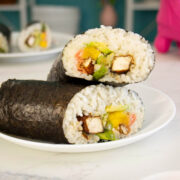 vegan sushi burrito sliced in half and stacked on a white plate