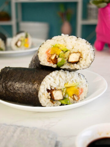 vegan sushi burrito sliced in half and stacked on a white plate