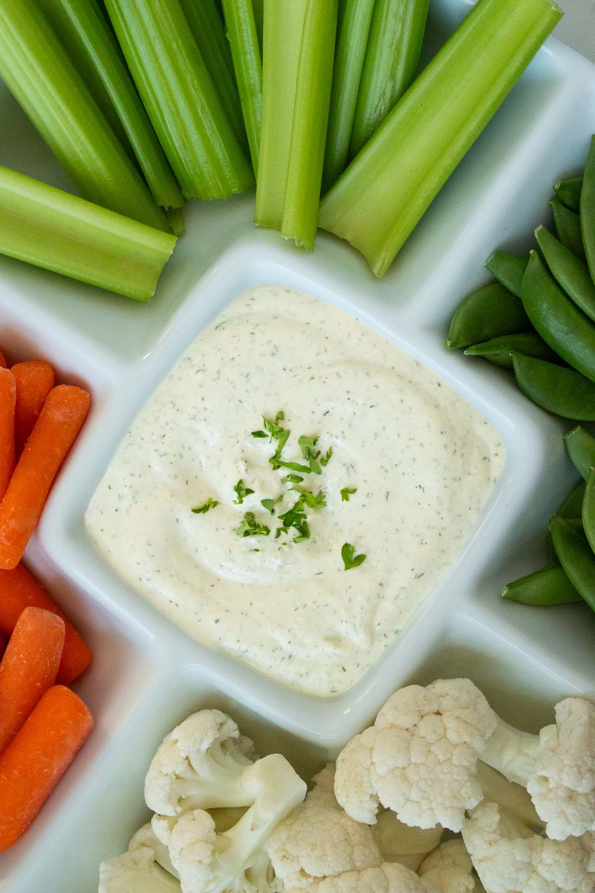 vegan dill dip with vegetables in a sectioned serving platter
