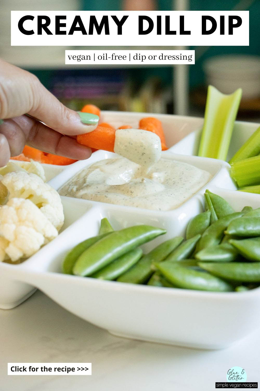 dipping a carrot into vegan dill dip on a tray surrounded by vegetables