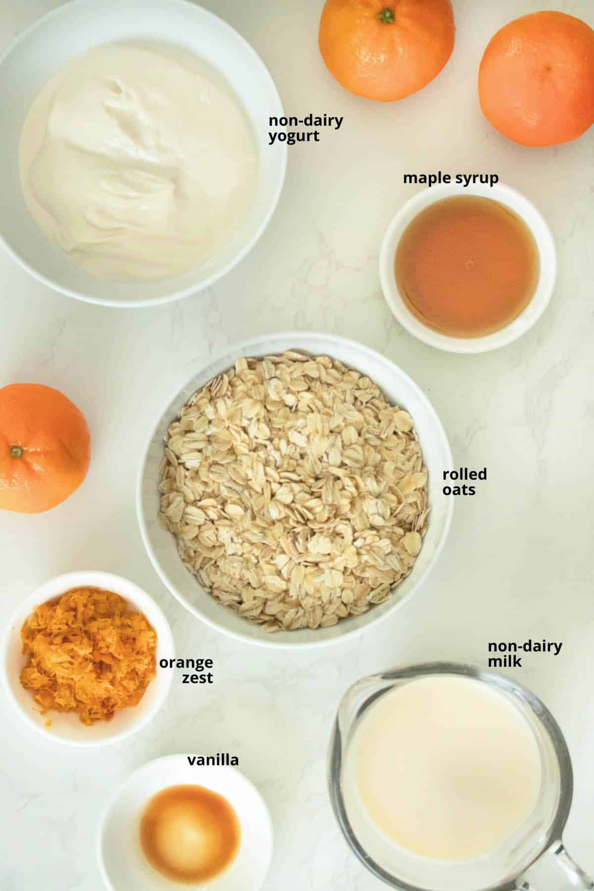 oats, orange zest, and other creamsicle oatmeal ingredients in bowls on a white table