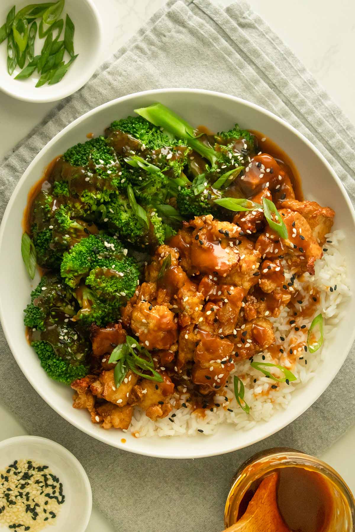 general tso's tofu in a white bowl with broccoli and rice