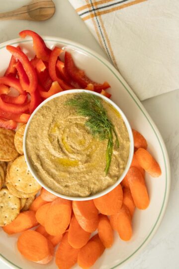 sunflower seed dip in a serving bowl with dill, veggies, and crackers