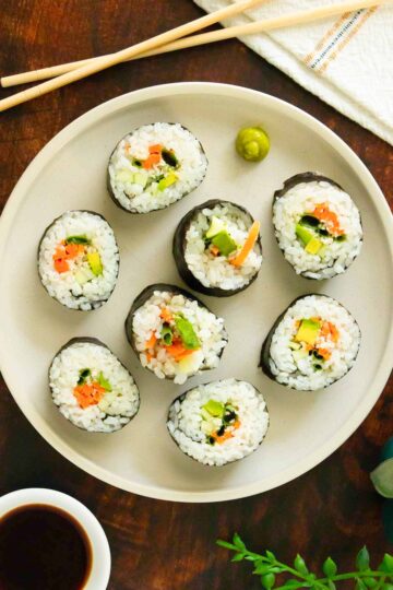 veggie sushi rolls on a plate with wasabi and soy sauce