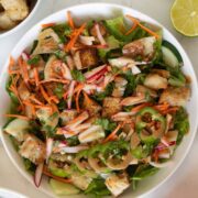 overhead photo of banh mi salad in a white bowl with ingredients around it
