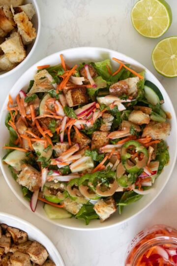 overhead photo of banh mi salad in a white bowl with ingredients around it