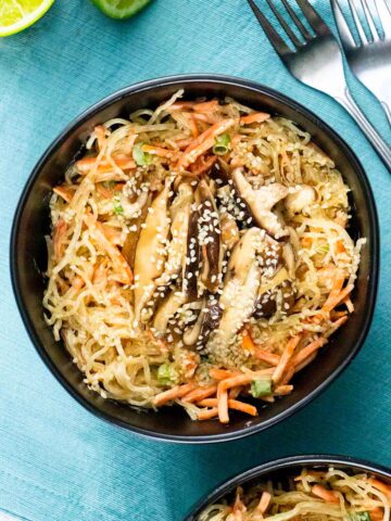 kelp noodle salad with carrots and green onions topped with shiitake mushrooms in a bowl