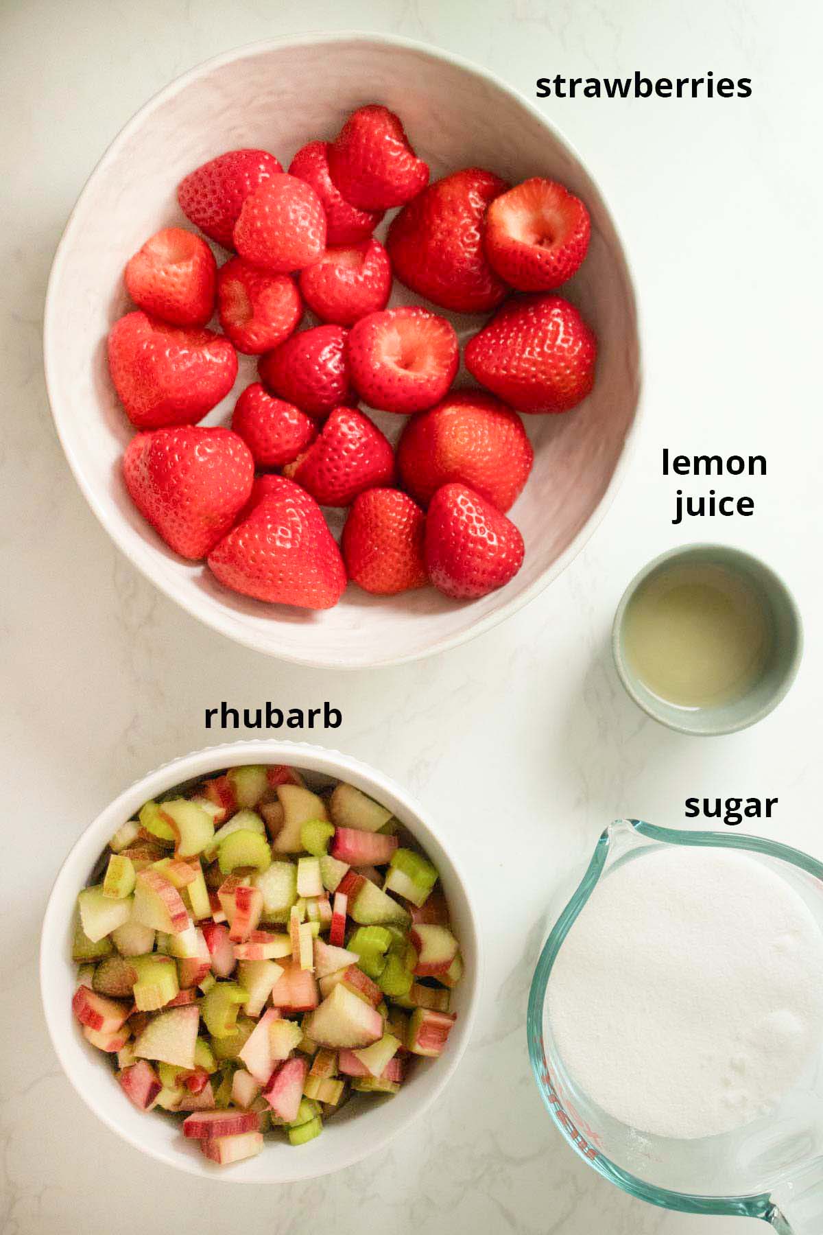 strawberry rhubarb freezer jam ingredients in bowls on a white table