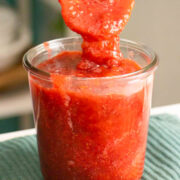 spooning strawberry rhubarb freezer jam into the jar