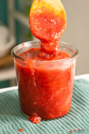spooning strawberry rhubarb freezer jam into the jar