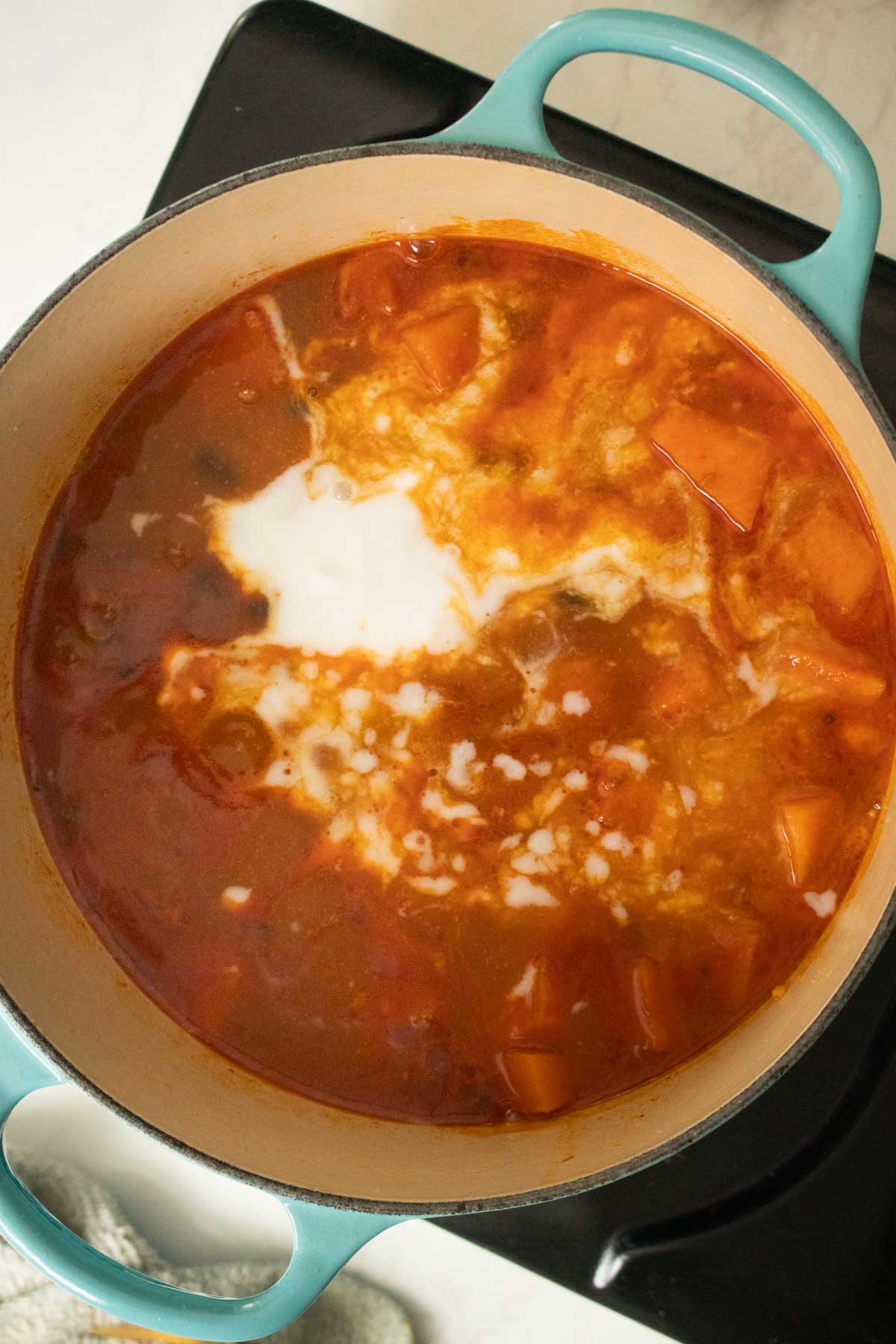 adding coconut milk to black bean sweet potato soup