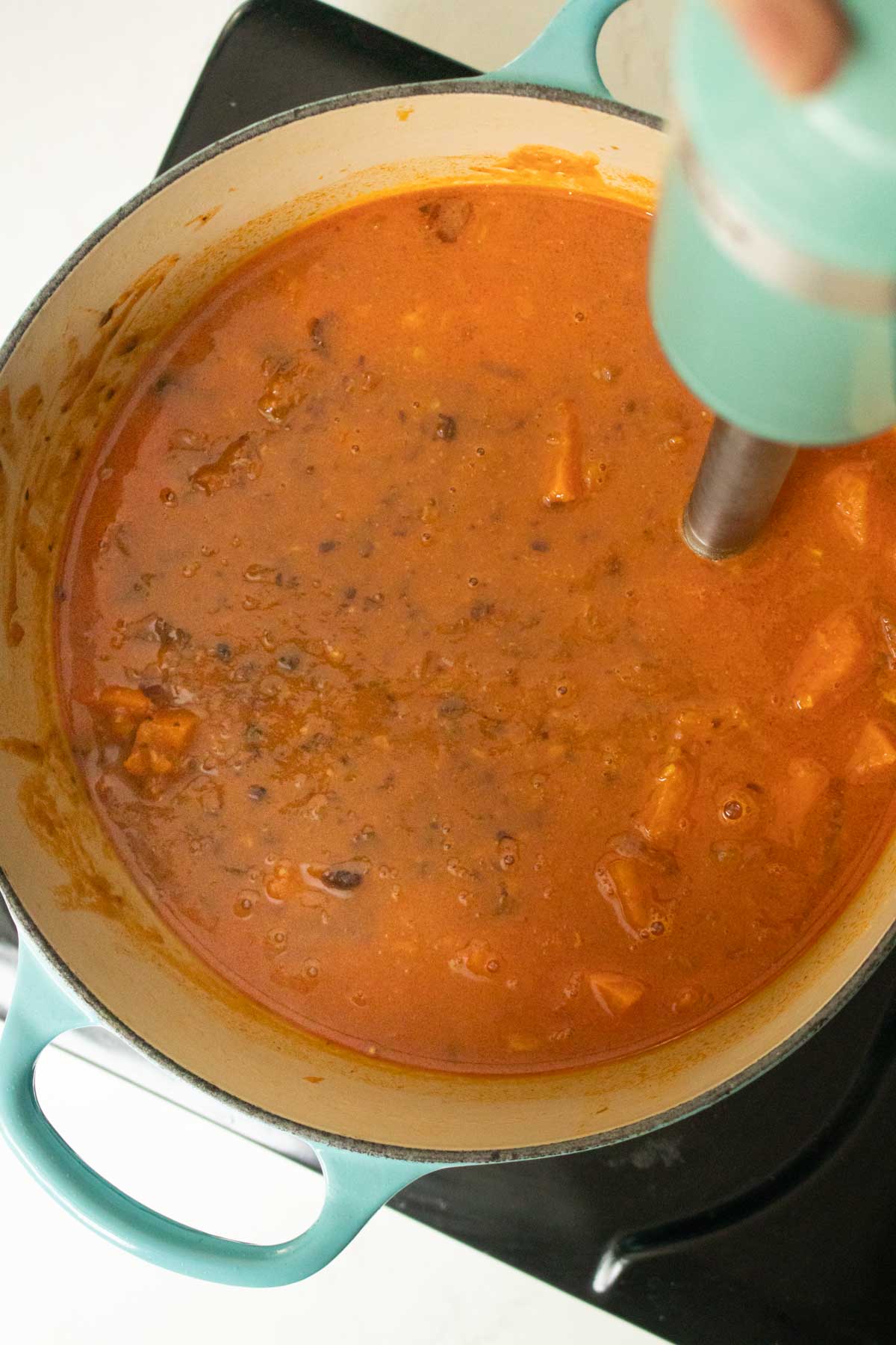 blending the black bean sweet potato soup for a thicker texture