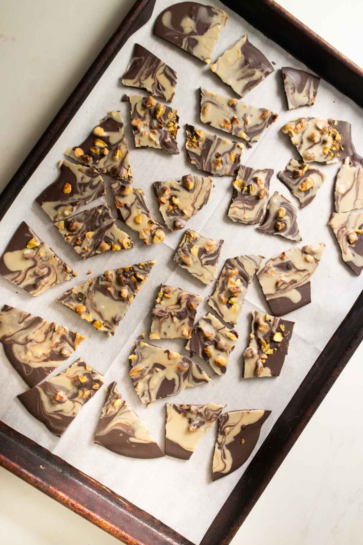 chocolate pistachio bark broken up on the baking sheet