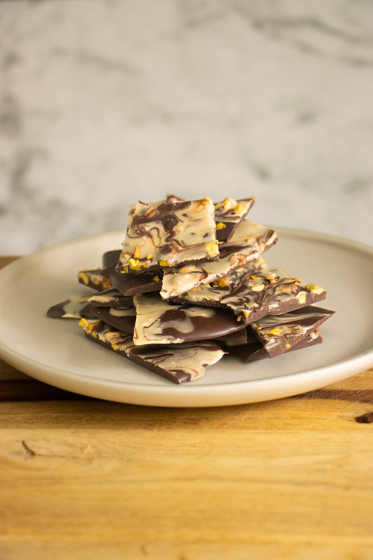side shot of chocolate pistachio bark on the plate, so you can see the thickness