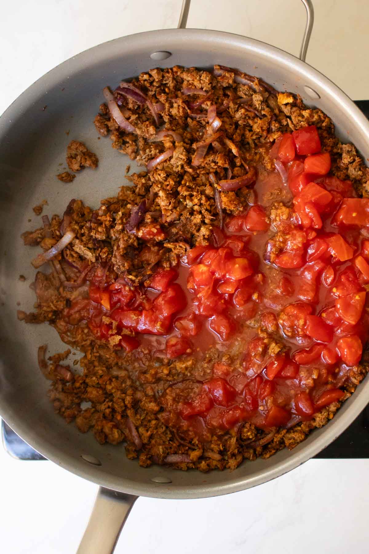 adding soy sauce and tomato to the pan