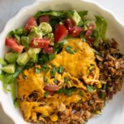 vegan taco casserole in a bowl with tomato avocado salad