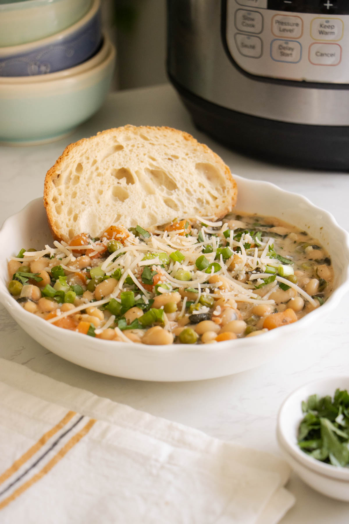 Instant Pot white bean soup with toppings and bread, Instant Pot in the background