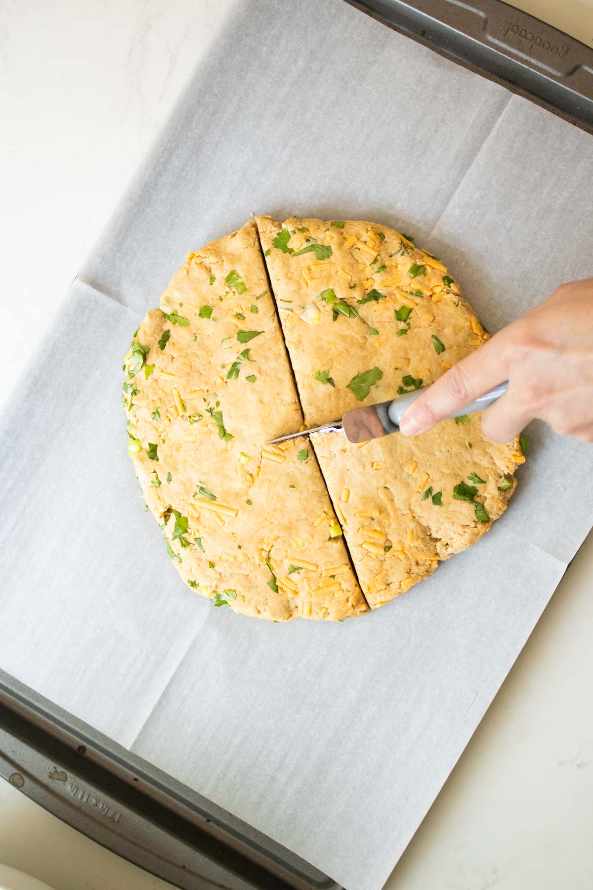 slicing the savory vegan scones dough into triangles with a pizza cutter