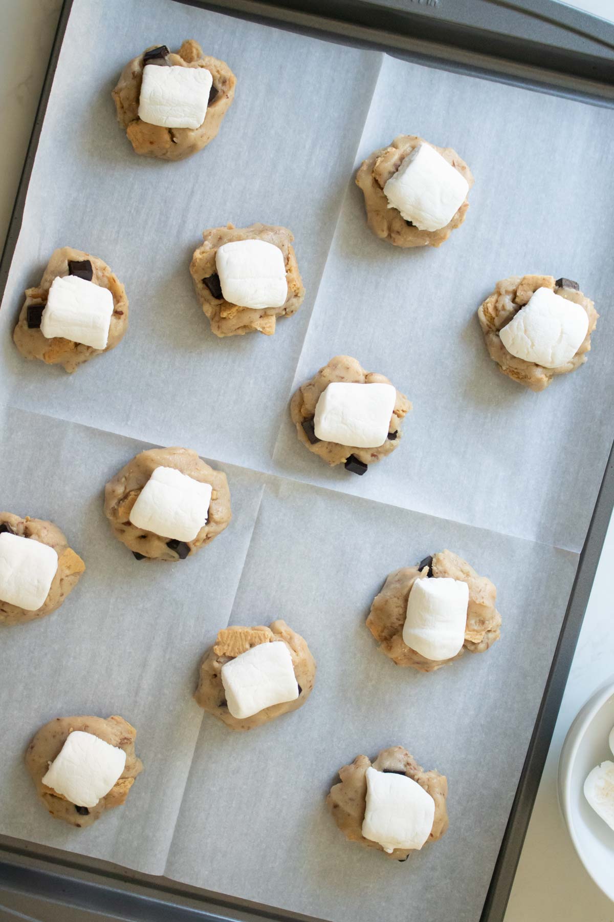vegan s'mores cookies on the baking sheet after adding the marshmallows on top