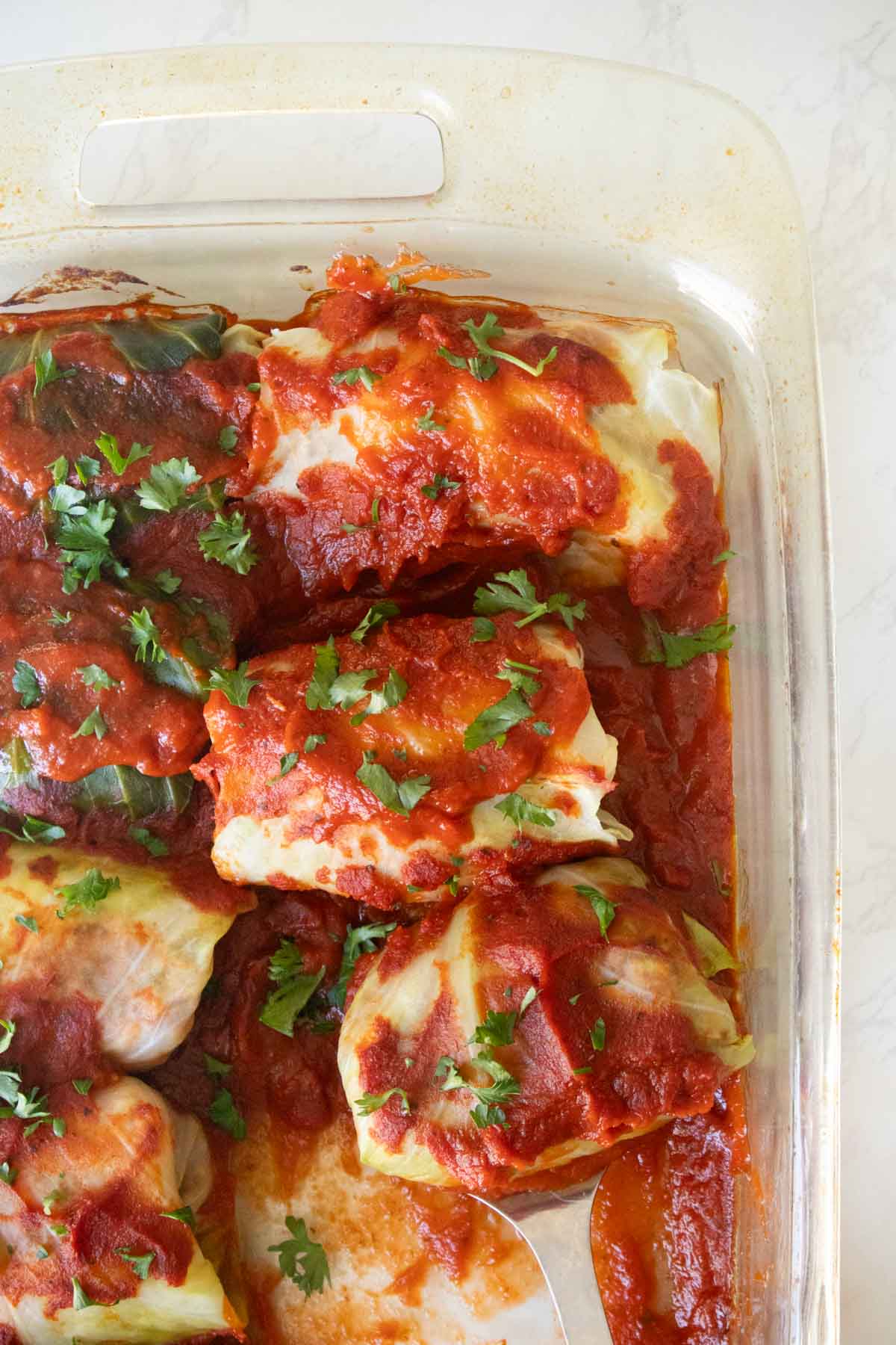 close-up of serving vegan cabbage rolls from the baking pan