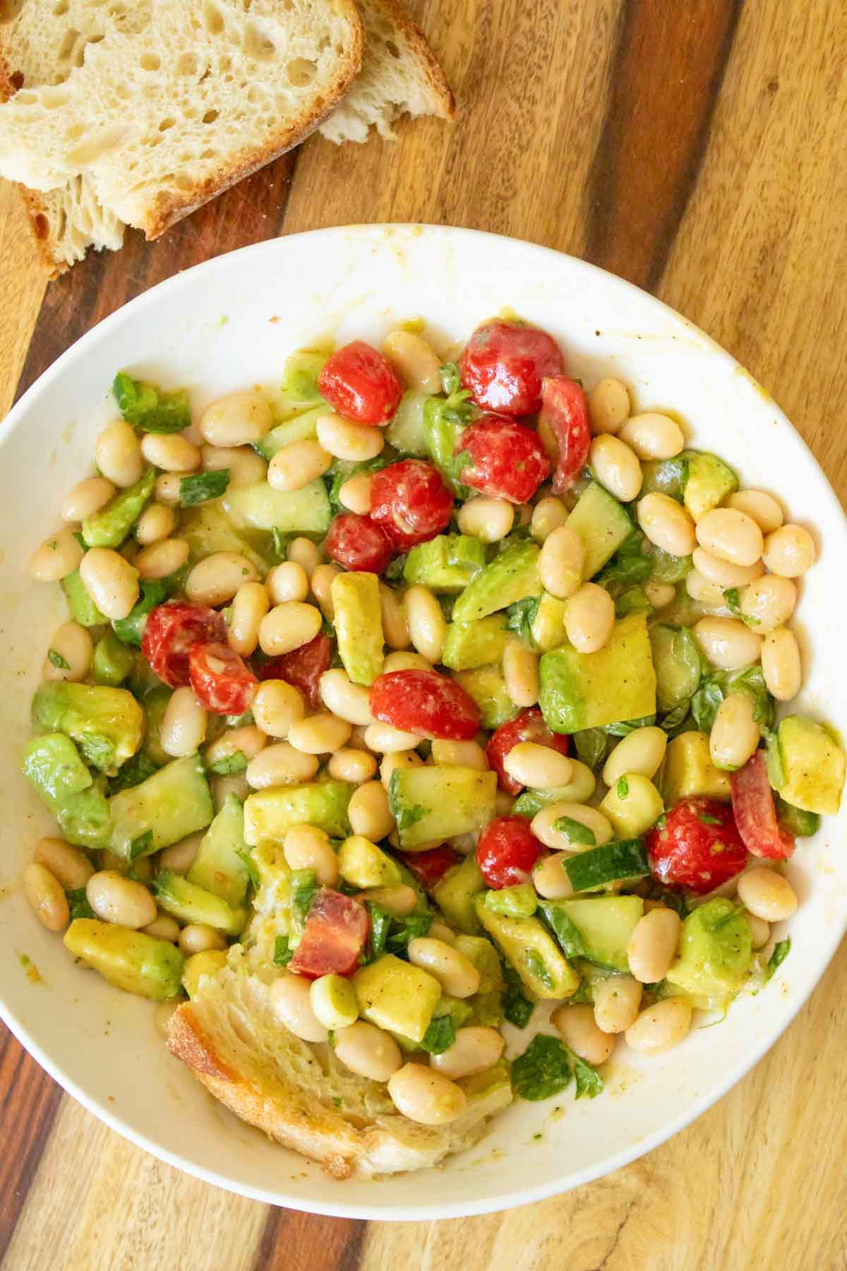 bowl of avocado white bean salad after dipping the bread