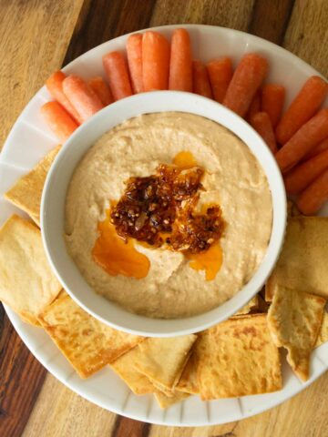 serving platter with chili crisp hummus, pita chips, and baby carrots