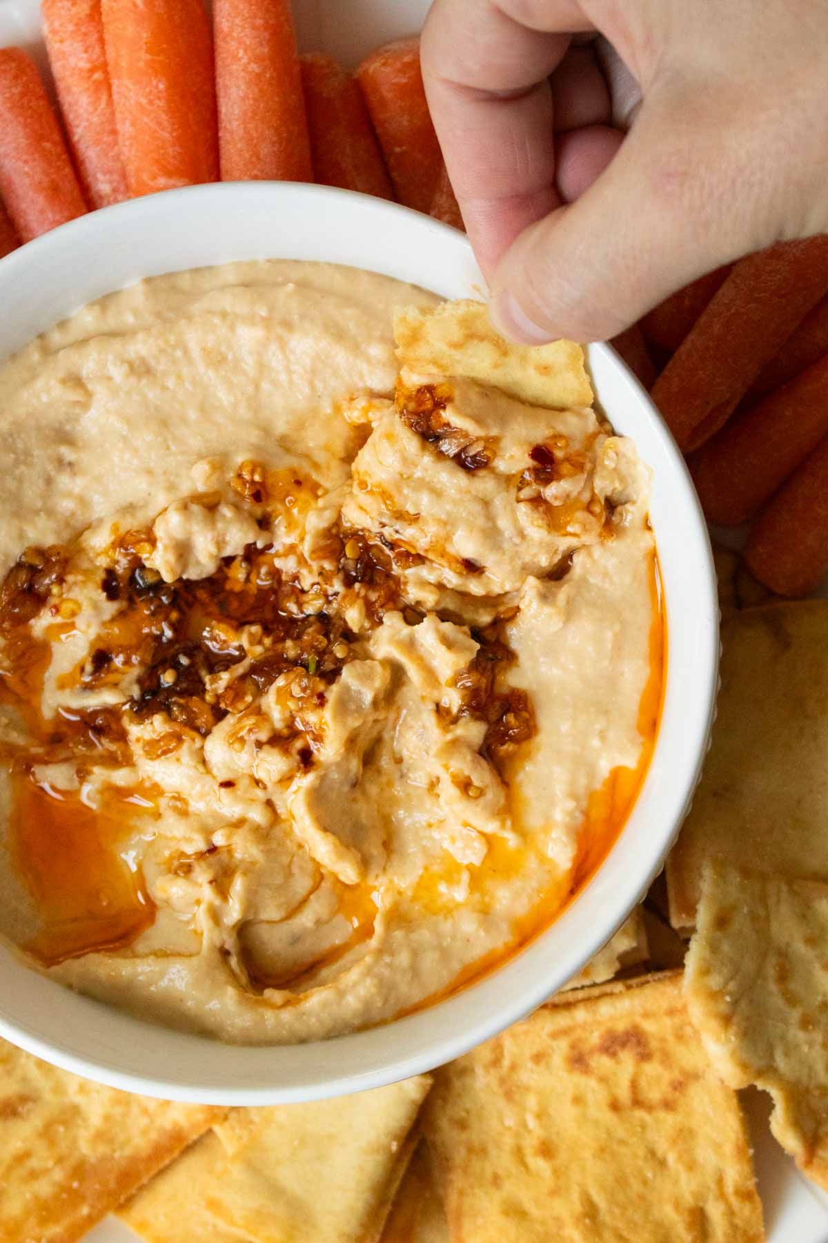 pita chip scooping up some spicy hummus