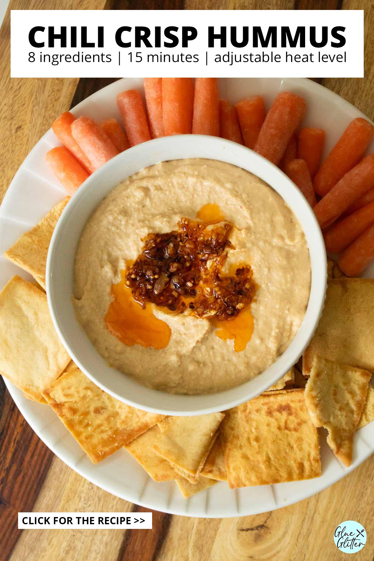 serving platter with chili crisp hummus, pita chips, and baby carrots, text overlay
