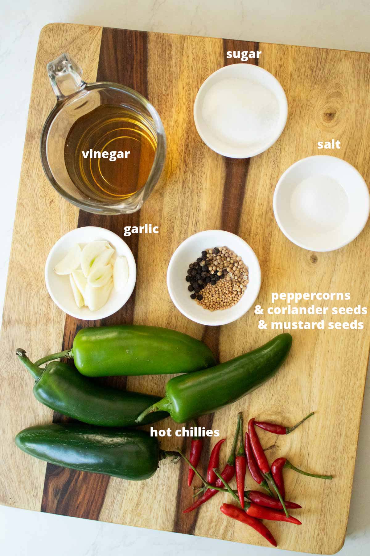 pickled chilies ingredients in bowls on a wooden cutting board, text labels