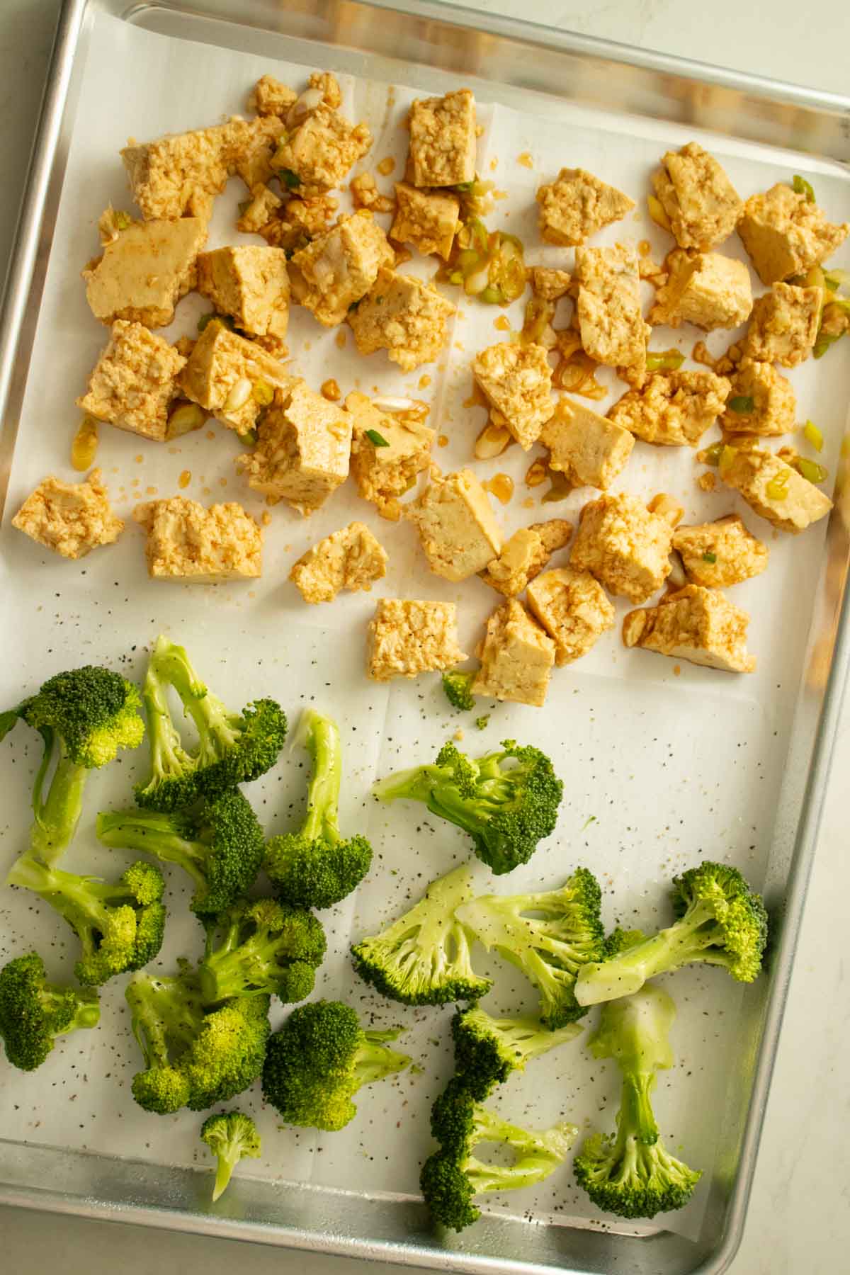 marinated honey garlic tofu on a sheet pan with broccoli before baking
